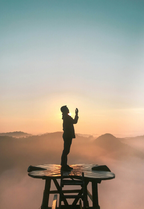 silhouette van man biddend in de bergen.