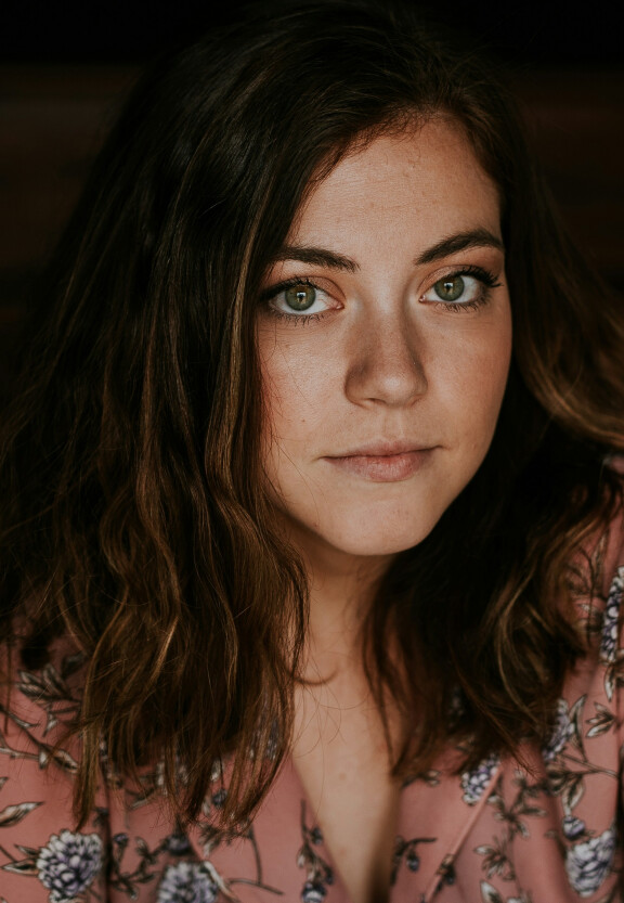 jonge vrouw met donker haar en groene ogen kijkt je aan