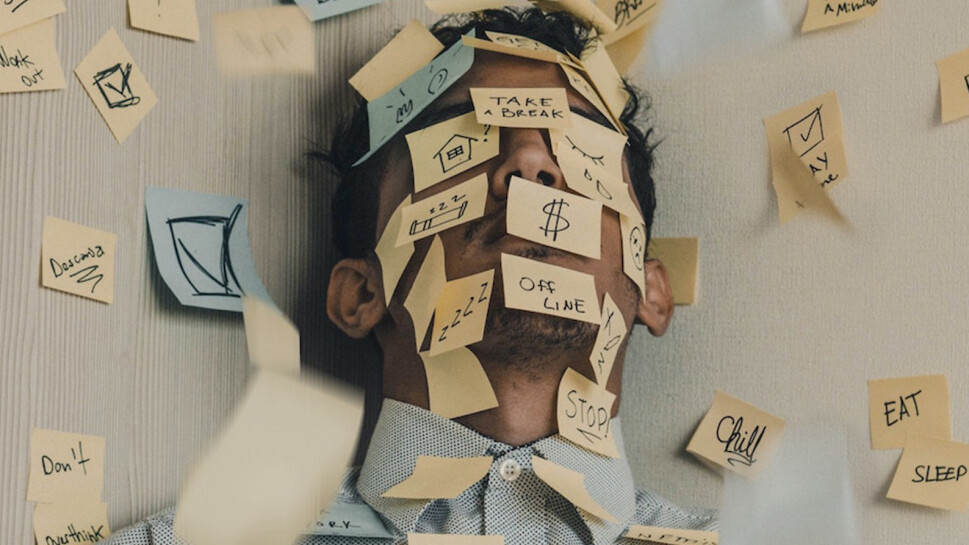 Man with stickynotes all over his face with the words of the things he is stressing about