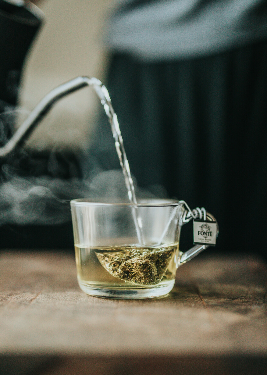 Hot water poured into a clear cup with a teabag